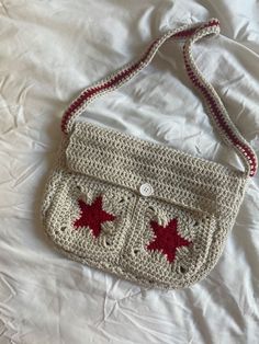 a crocheted purse sitting on top of a white bed next to a pillow