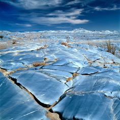 the rocks are covered in ice and snow under a blue sky with wispy clouds