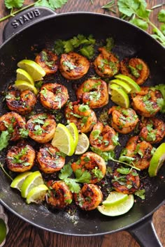 shrimp in a skillet with limes and cilantro garnishes