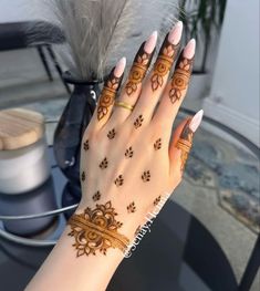 a woman's hand with hennap and feathers on top of her arm