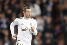 a male soccer player is running with the ball in his hand and fans are behind him