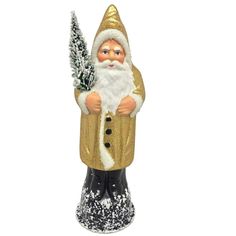 a santa clause figurine holding a christmas tree in his hand and wearing a gold coat