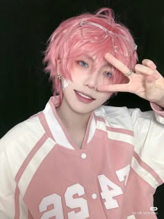 a man with pink hair and glasses making the peace sign while wearing a football uniform