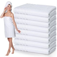 a woman standing next to a stack of white towels