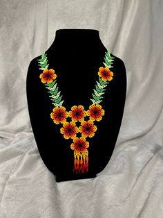 the necklace is decorated with flowers and leaves on a black mannequin head stand