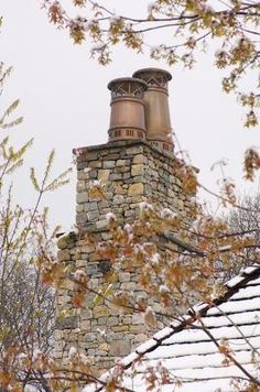 an old brick chimney on top of a house in the winter with leaves around it