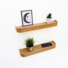 two wooden shelves with plants and a cell phone on one shelf next to the other