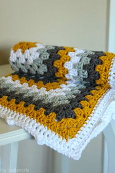 a crocheted blanket sitting on top of a white table next to a wall