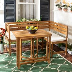 a wooden table with two chairs and a bowl of fruit on it in front of a window