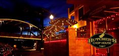 the entrance to butcher's chop house at night with lights and bikes parked outside