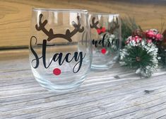 two wine glasses sitting on top of a wooden table next to christmas decorations and greenery