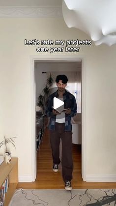 a man standing in a living room holding a piece of paper with the caption let's rate my projects one year later