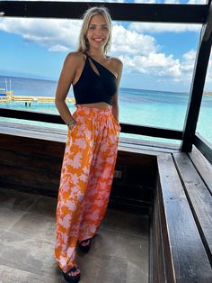 Take a walk on the sunny side with these Feeling Tropical Flowy Wide Leg Pants! With an elastic waistband and adjustable drawstring, these lightweight, sun-ready pants are perfect for any outdoor adventure. Featuring a wide-leg fit and all-over tropical prints, these amazing pants will make you look fabulous while you have fun in the sun! Color: Orange Tropic Fabric: 100% Polyester Brand: Lumiere Includes: x1 Pair of Pants Sizes: S-M-L, Regular Sizing Model is 5'9" and wearing a size Small Casual Vacation Bottoms With Drawstring, Summer Outdoor Relaxed Fit Parachute Pants, Beachy Bottoms With Pockets For Vacation, Tropical Vacation Pants With Elastic Waistband, Beachy Vacation Bottoms With Pockets, Beach Wide-leg Pants With Drawstring, Casual Parachute Pants For Beach, Tropical Style Summer Pants With Elastic Waistband, Summer Vacation Bottoms With Drawstring