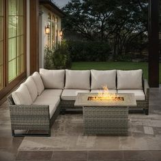 a fire pit sitting on top of a patio next to a couch and table in front of a house