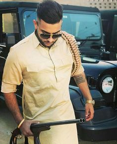 a man with sunglasses and a snake wrapped around his arm walking towards a black car