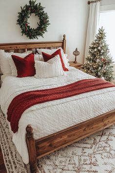 a bed with red and white pillows on top of it next to a christmas tree