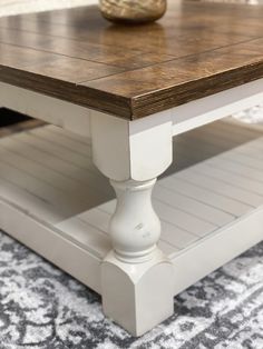 a wooden table sitting on top of a carpeted floor next to a white vase