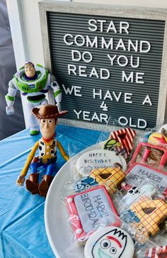 toy story themed cookies on a table with a sign in the background that says, star command do you read me we have a year old