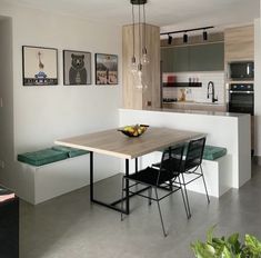 a kitchen with a table, chairs and pictures hanging on the wall in front of it