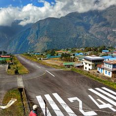 a man standing on the side of a road next to a lush green mountain range