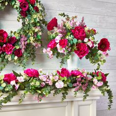 red and pink flowers are arranged on the mantle