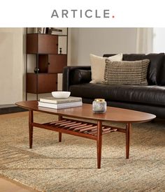 a living room with a couch, coffee table and books on the floor in front of it