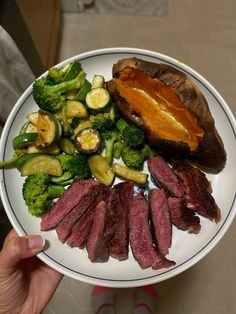 a white plate topped with steak, broccoli and other foods on top of it