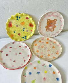 four plates with different designs on them sitting next to each other in front of a white wall