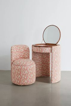 an upholstered vanity and stool with a mirror on the top, in front of a white wall