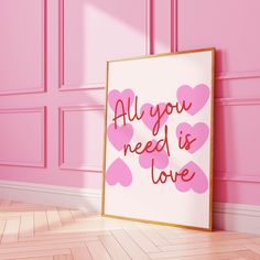 an all you need is love sign in front of a pink wall with hearts on it