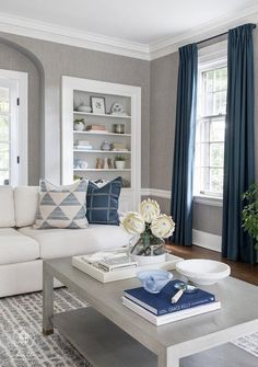 a living room with white furniture and blue curtains