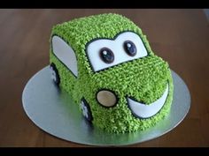 a green cake with cars on it sitting on top of a table