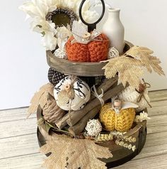 an arrangement of knitted pumpkins and other fall decorations on a wooden table top