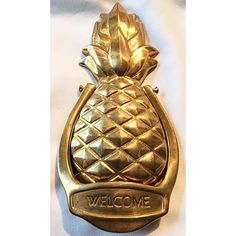 a gold pineapple shaped bottle opener with the word welcome on it's side