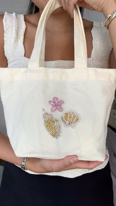 a woman holding a white bag with gold and pink butterflies on it