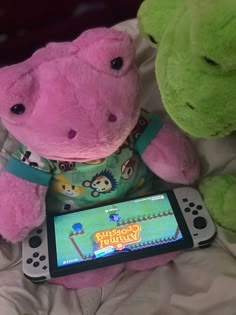 two stuffed animals sitting on top of a bed next to a nintendo wii game controller