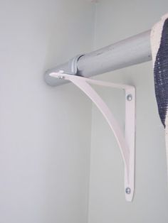 the corner of a room with a curtain rod on it and a towel rack attached to the wall