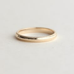 a gold wedding band on a white surface with the word love engraved in it's center