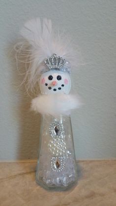 a glass vase with a snowman in it on a table next to a wall