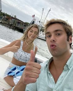 a man and woman on a boat giving the thumbs up sign while sitting in front of them