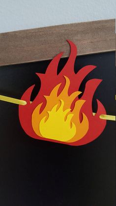 a fire sign hanging from the side of a door with yellow and red flames on it