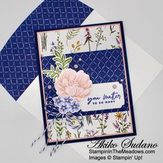 a close up of a greeting card with flowers on the front and blue envelope in the back