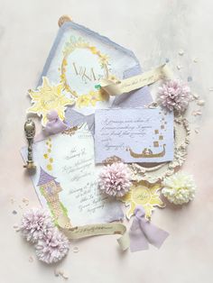 an assortment of papers and flowers on a pink tablecloth with gold trimmings