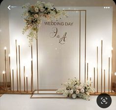 a wedding day set up with candles and flowers on the floor in front of a backdrop