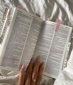 a person laying in bed reading a book with their hands on top of the book