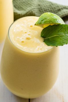 a smoothie with a green leaf garnish on the top and another drink in the background