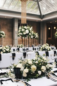 the tables are set with white flowers and black place settings for an elegant wedding reception