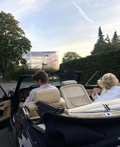 two people sitting in the back of a convertible car