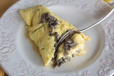 a white plate topped with an omelet and a fork