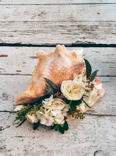 a bouquet of flowers and seashell on a wooden surface